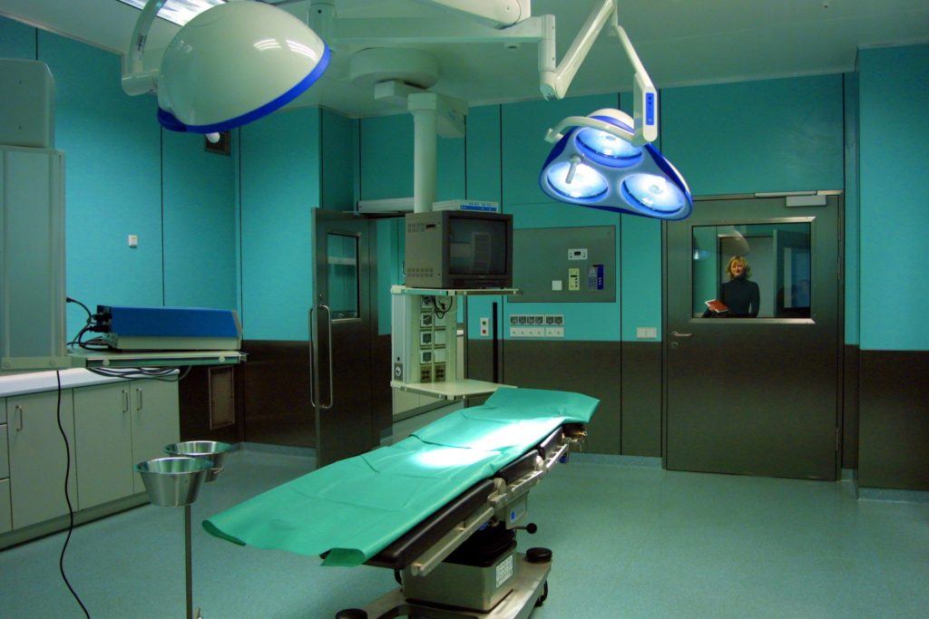 modern surgical room with bright lights, green table, and advanced equipment for procedures.