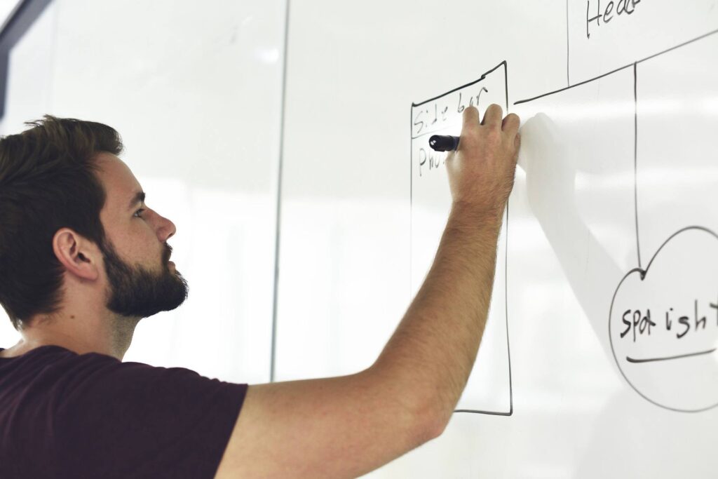 creative teamwork: man brainstorming on whiteboard in modern office for innovative ideas.