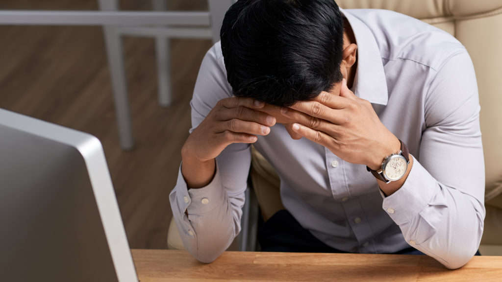 a man sitting at a desk with his head in his hands