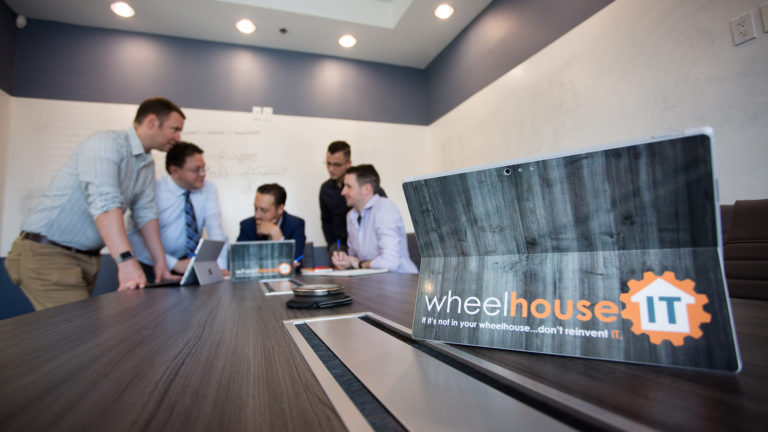 collaborative professionals discussing it solutions in modern conference room with wheelhouse it logo.