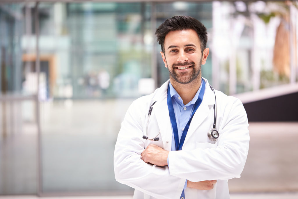 a man in a white coat is standing with his arms crossed