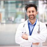 a man in a white coat is standing with his arms crossed