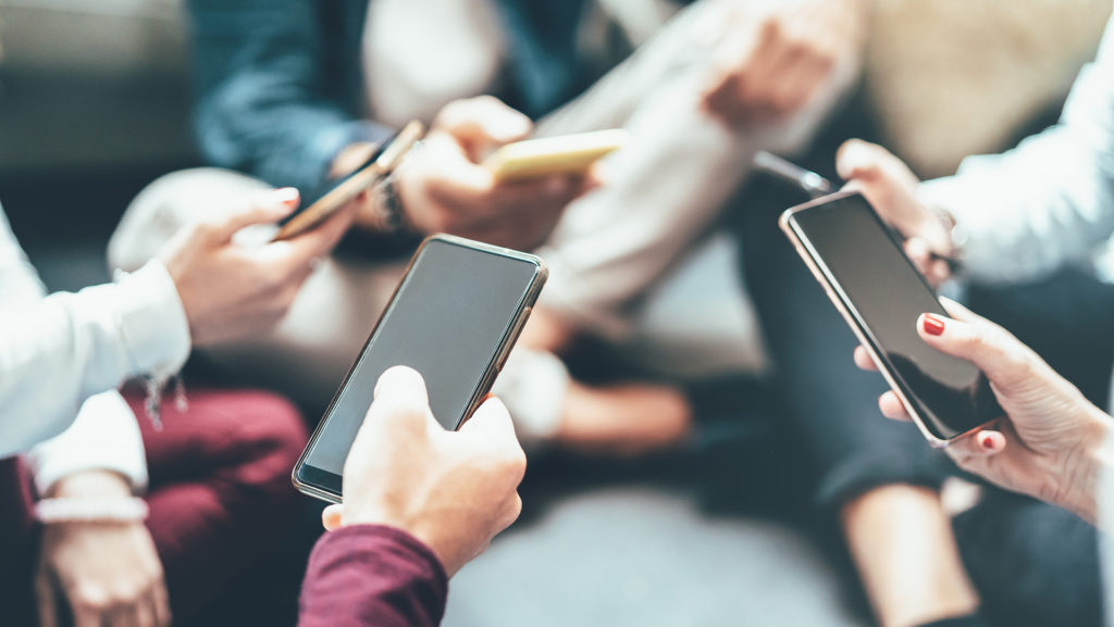 diverse group using smartphones in cozy setting for modern social interaction.