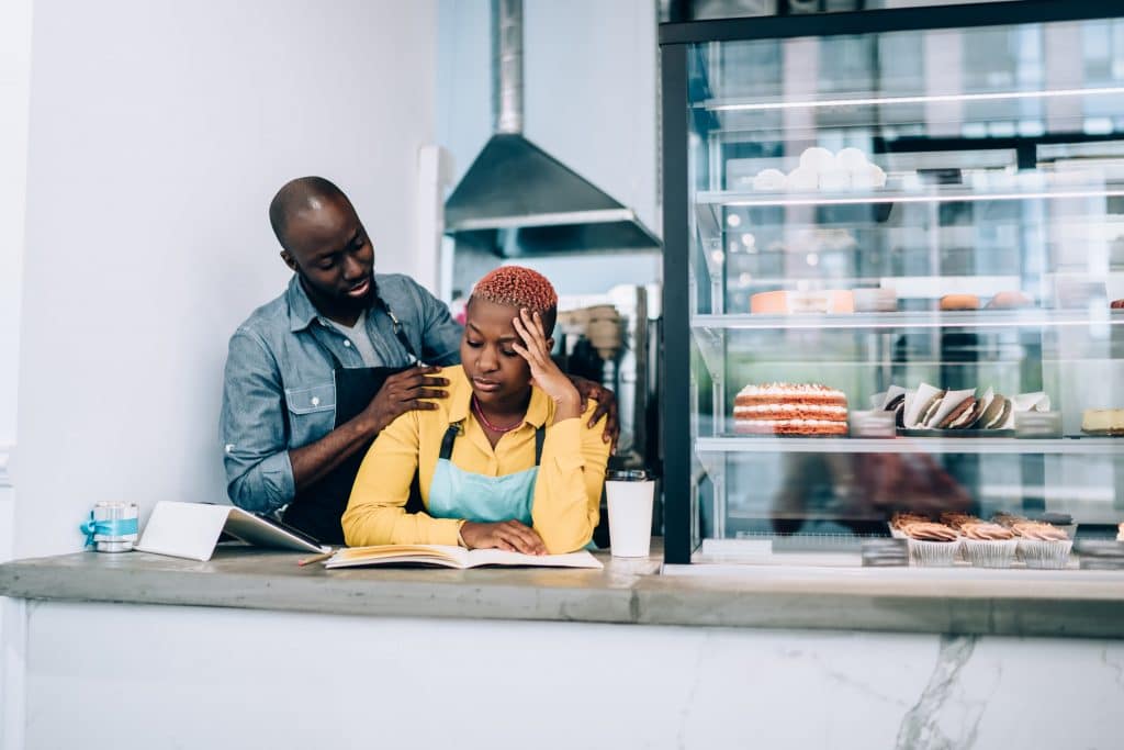 supportive teamwork in a cozy café with man and woman discussing business operations.