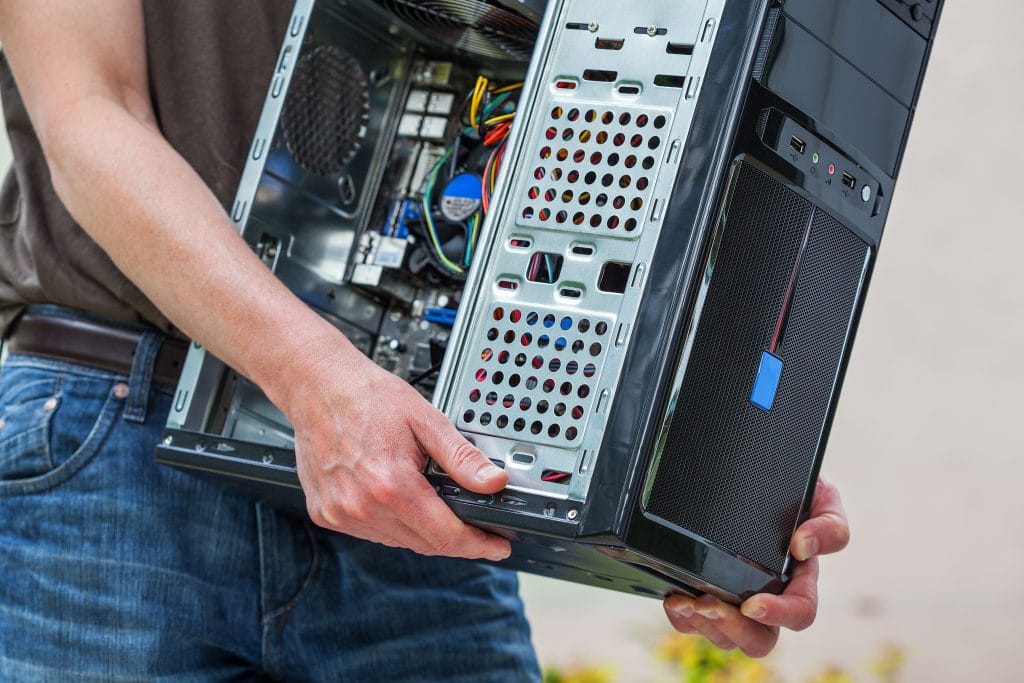 carefully holding black computer tower with colorful wiring, possibly for upgrade or repair.