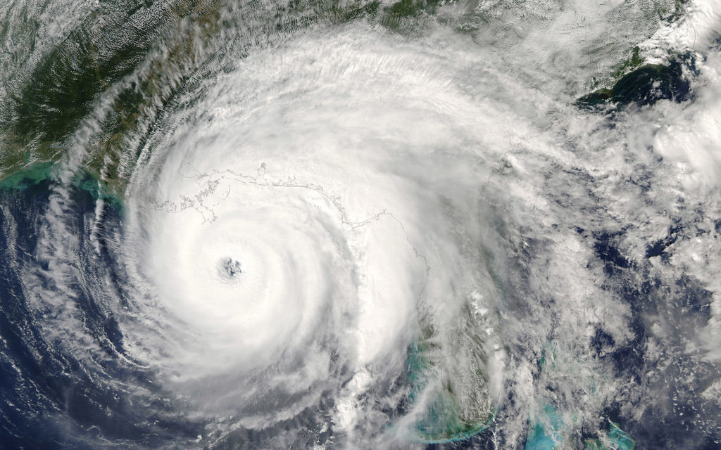 swirling hurricane storm viewed from satellite showing dense clouds, eye, and ocean bands.