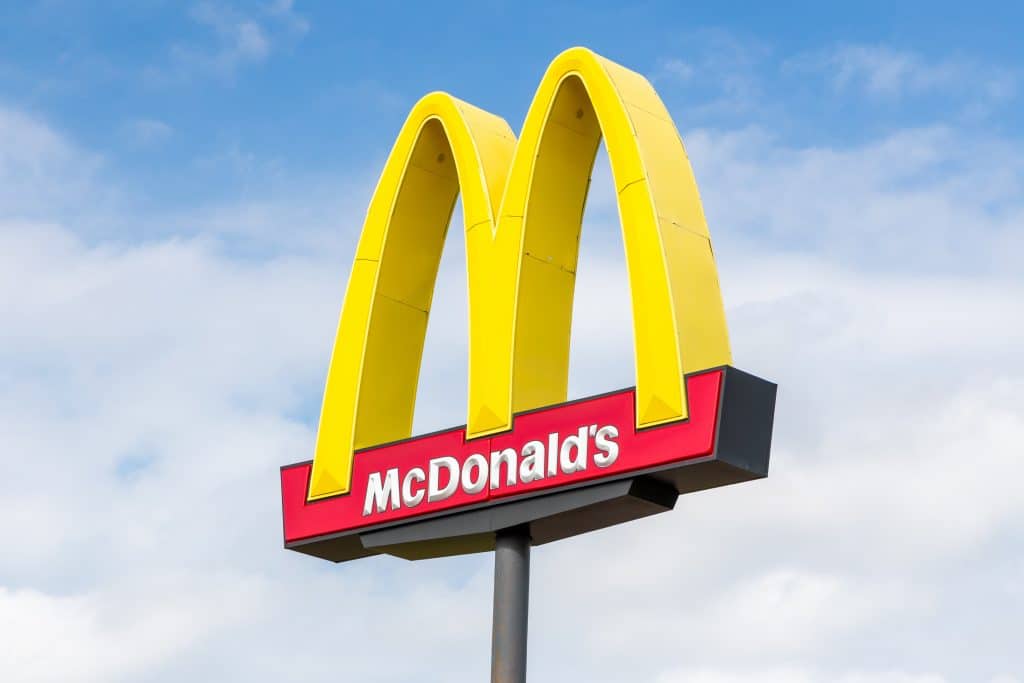 iconic mcdonalds logo under clear blue sky, symbolizing fast food convenience worldwide.