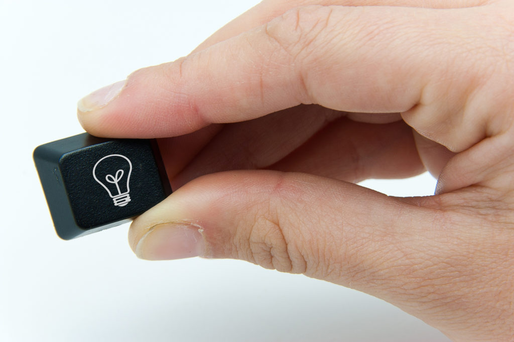 creative hand holding light bulb keycap symbolizing ideas.