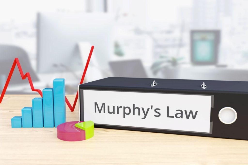 navigating challenges: binder labeled murphys law surrounded by colorful data graphs in office.