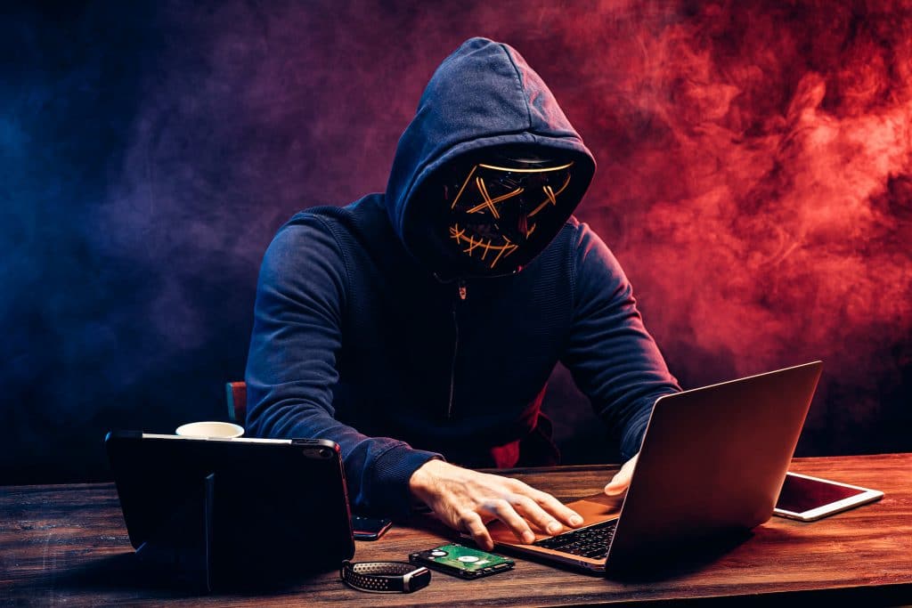 enigmatic hacker in skull mask working on laptop in cyberpunk setting.