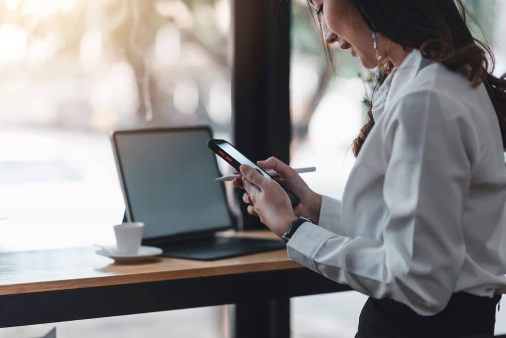 woman in modern workspace, focused on smartphone during break.