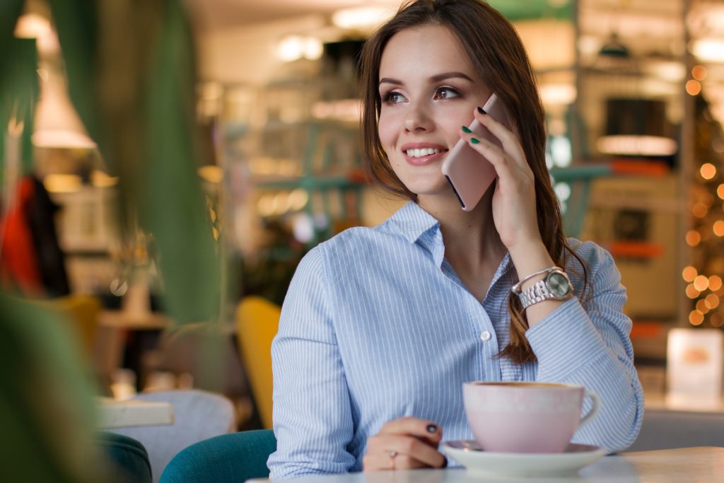 serene woman enjoying phone call in cozy café with pink teacup.