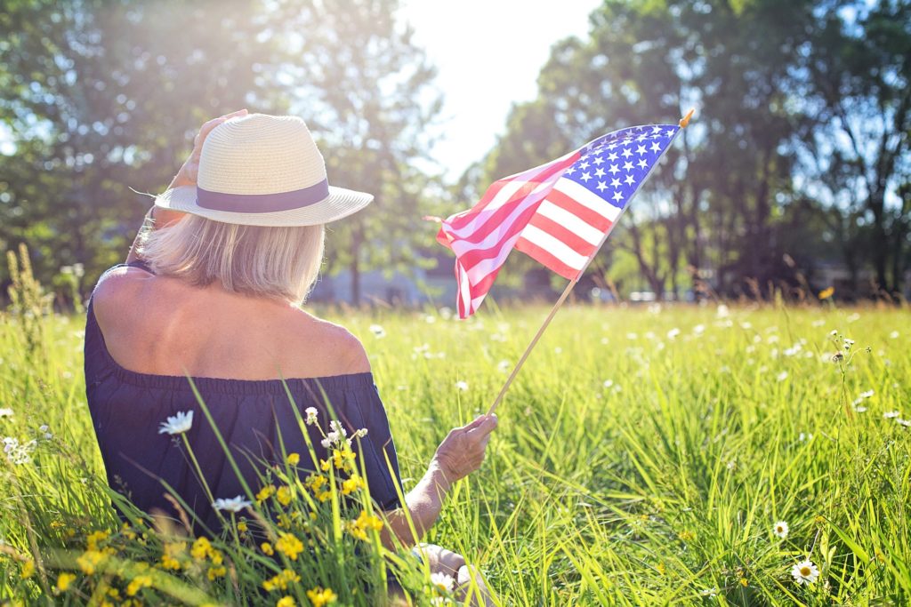 woman relaxing in sunny field with american flag, embodying patriotism and leisure.