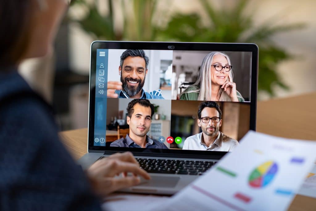 diverse professionals collaborate in virtual team meeting surrounded by greenery and documents.