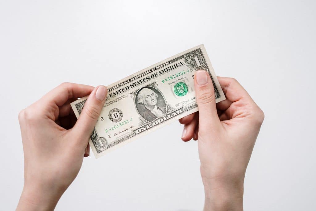 close-up of hands holding u.s. one-dollar bill, showcasing currency details and significance.