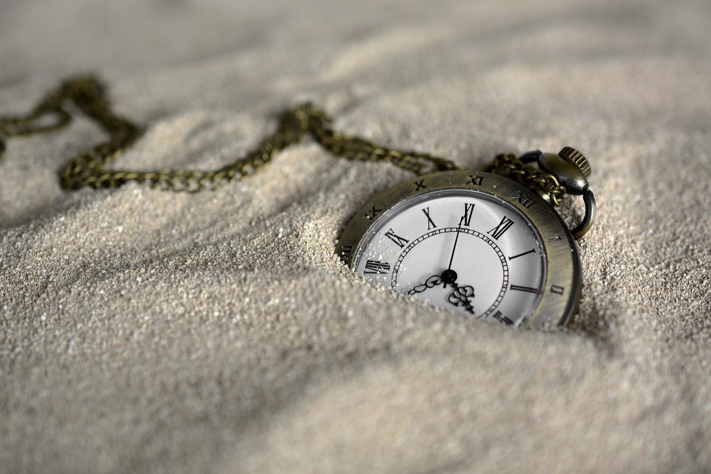 vintage pocket watch in sand, capturing the essence of times fleeting beauty.