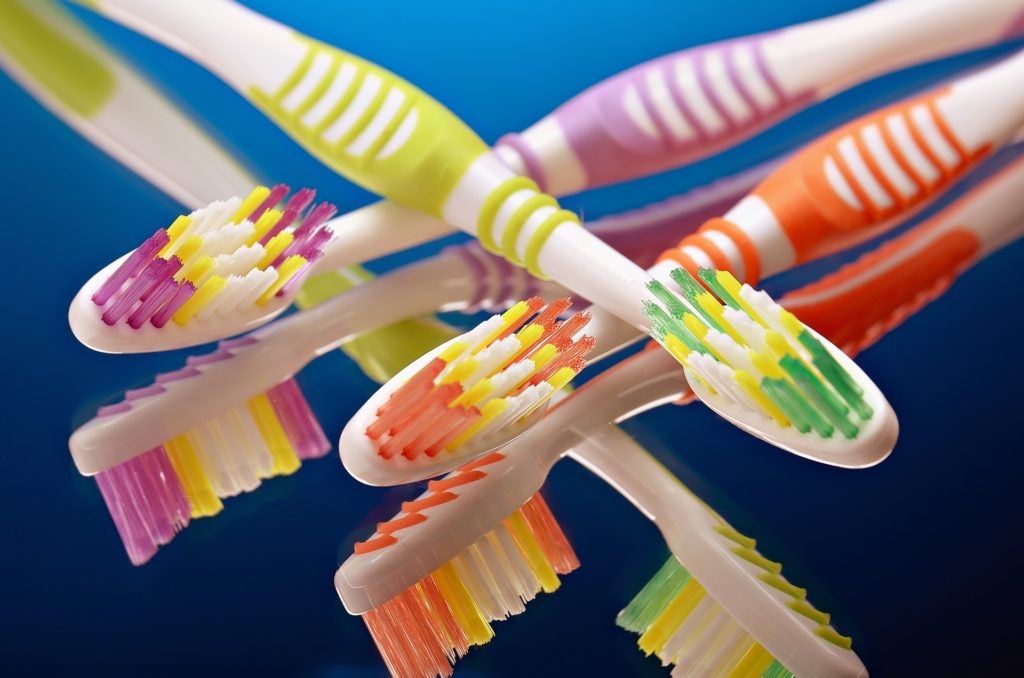 colorful toothbrushes against vibrant blue background, promoting fun dental hygiene.