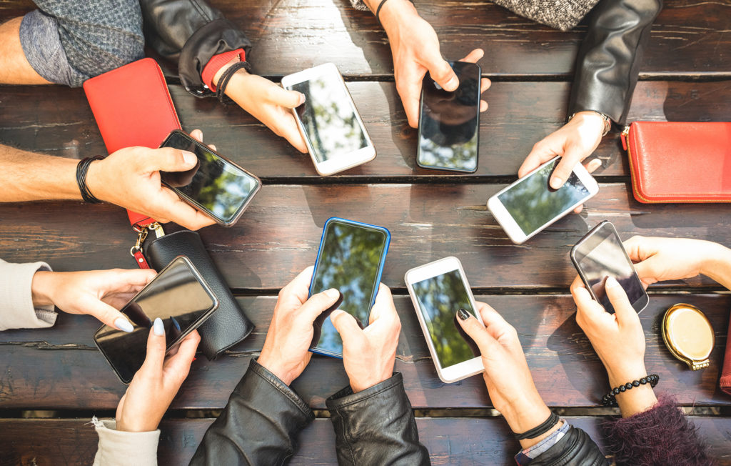 gathering of friends using smartphones outdoors, reflecting modern social interaction.