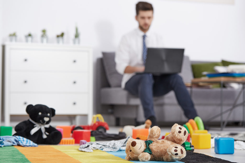 modern family home: father works on laptop surrounded by kids toys.