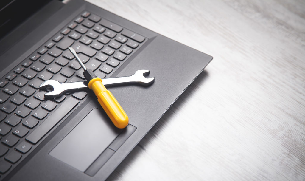 laptop repair essentials: wrench & screwdriver on modern laptop.