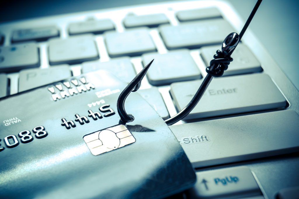 beware of phishing: credit card hooked on keyboard, emphasizing online fraud risks.