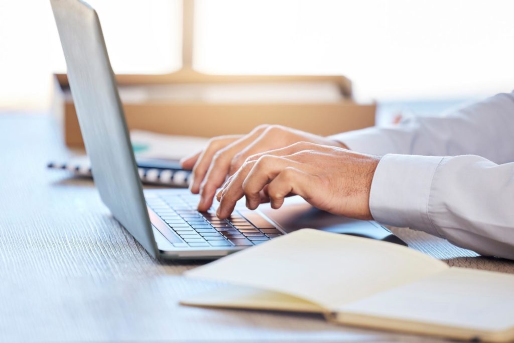 professional businessman typing on laptop keyboard in modern office setting.