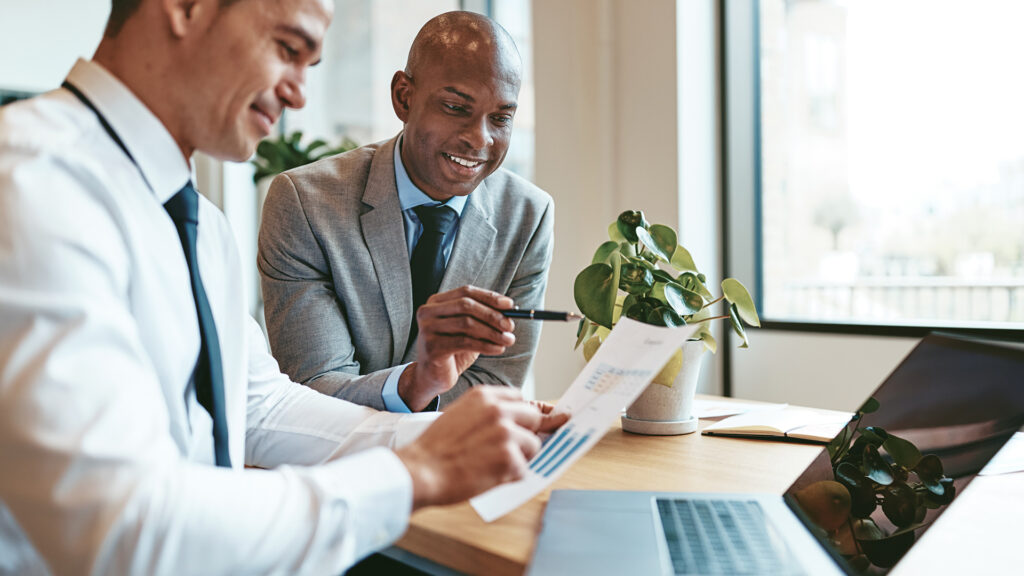 professional men collaborate in modern office discussing business strategies, blending technology with traditional methods.