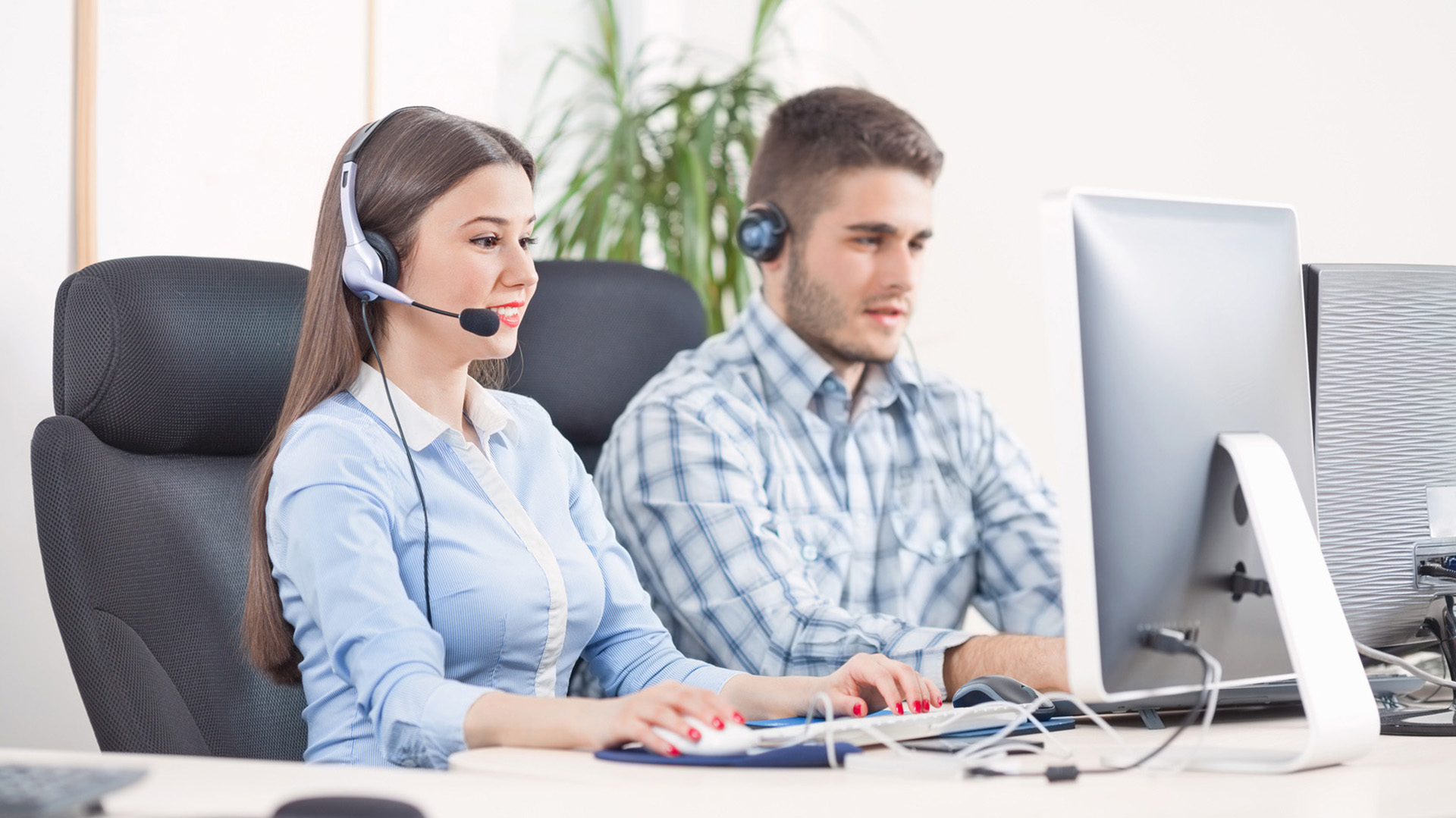 a man and woman sitting at a desk with headsets on