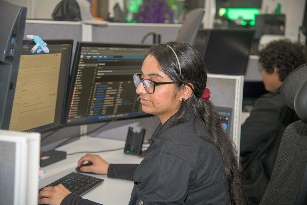 busy modern office environment with woman working on dual computer monitors.