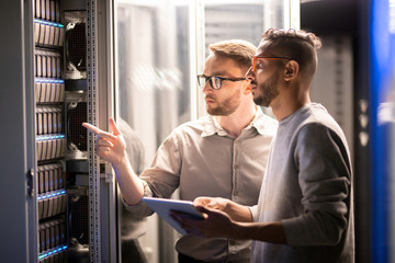 two professionals discussing technical matters in a modern data center with illuminated server racks.