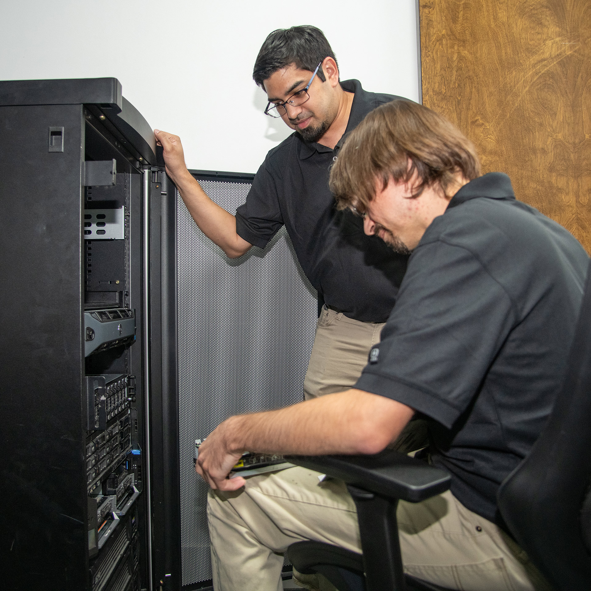 two technicians collaborating on a server room inspection for technology equipment maintenance.