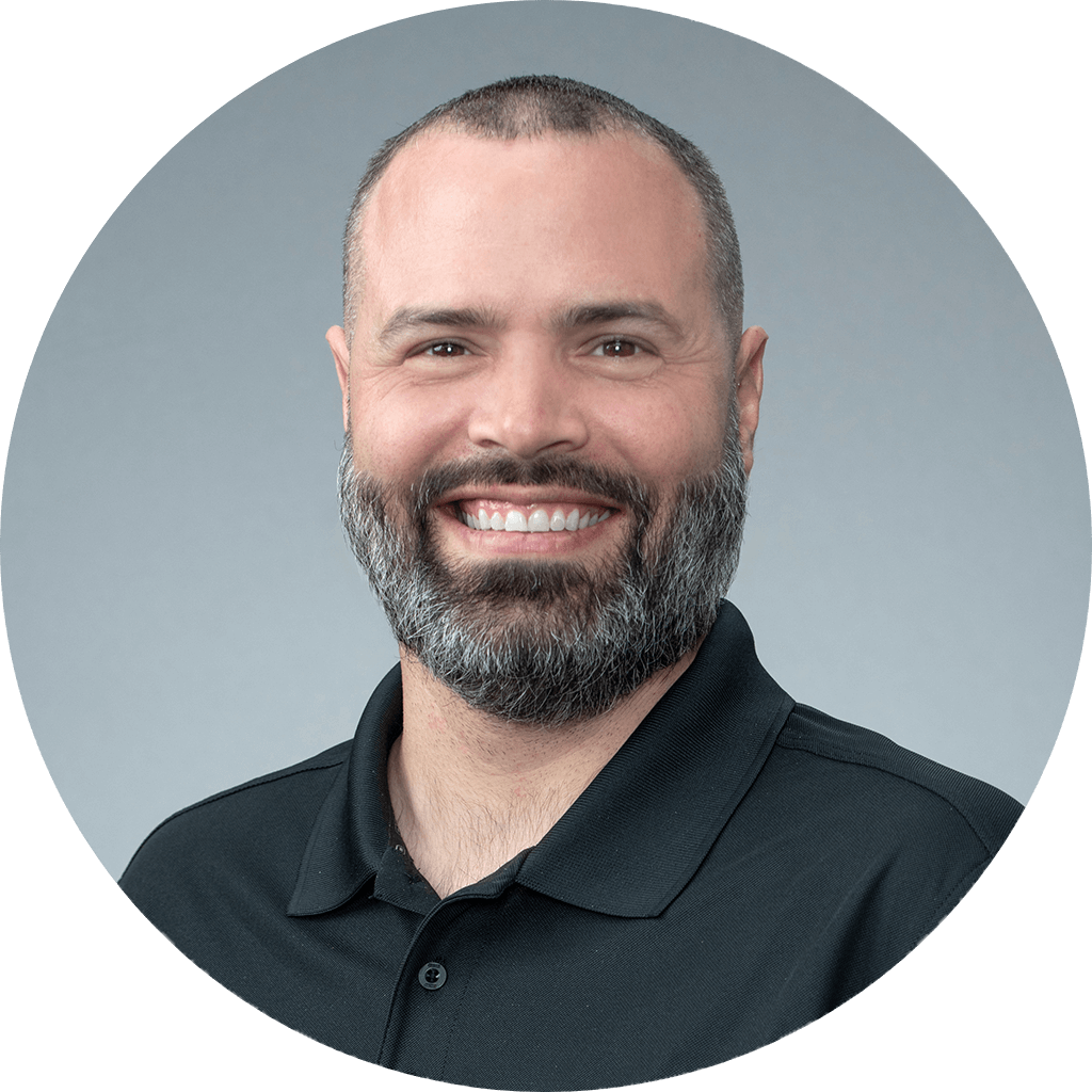 friendly man in professional headshot with warm smile, black polo shirt, and engaging expression.