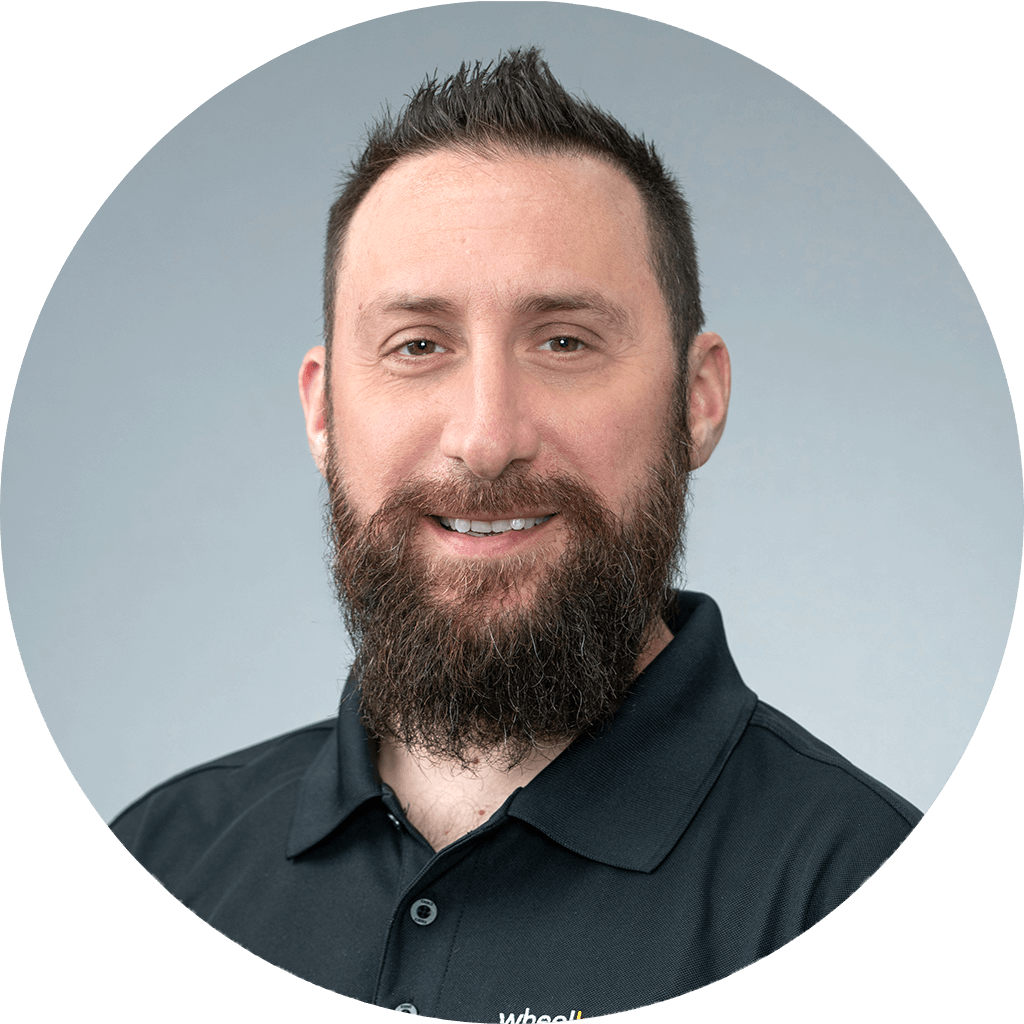 man with well-groomed beard and friendly smile in professional black polo portrait.