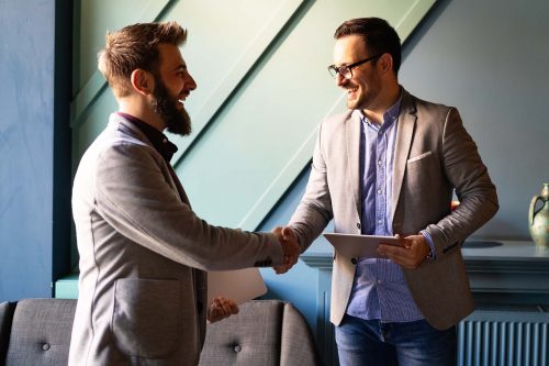 two men shaking hands over a piece of paper