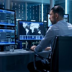 tech professional analyzing cybersecurity data in modern office with city lights outside.