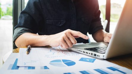 data-driven professional working on analysis with charts, graphs, and laptop in well-lit workspace.