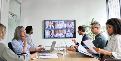 global team in modern boardroom on virtual call, promoting collaboration & teamwork.